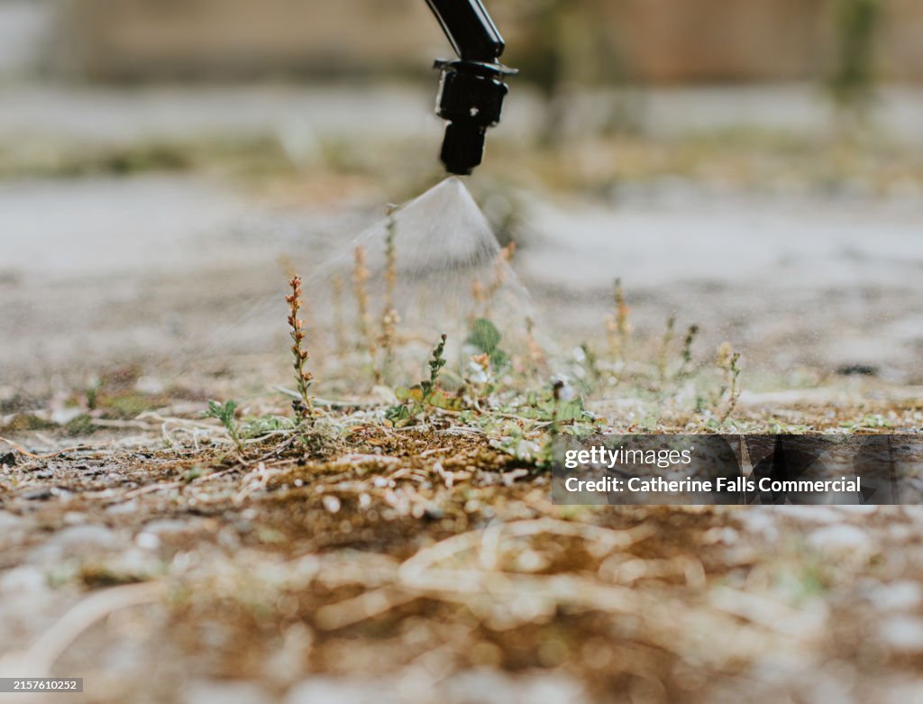 Close-up of a nozzle spraying weed killer on weeds