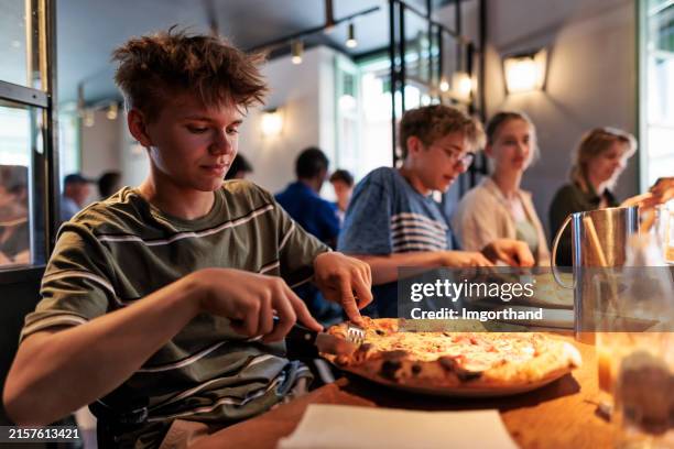 family enjoying pizza in a restaurant - pizza restaurant stock pictures, royalty-free photos & images