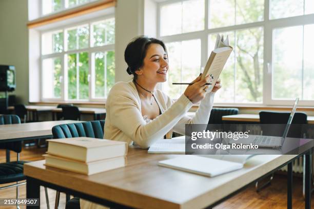 dissertation work: smiling woman immerses herself in books for her research in library. - dictionnaire photos et images de collection