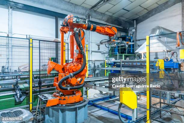 modern robotic arm in a factory generating metal pieces - industria pesada fotografías e imágenes de stock