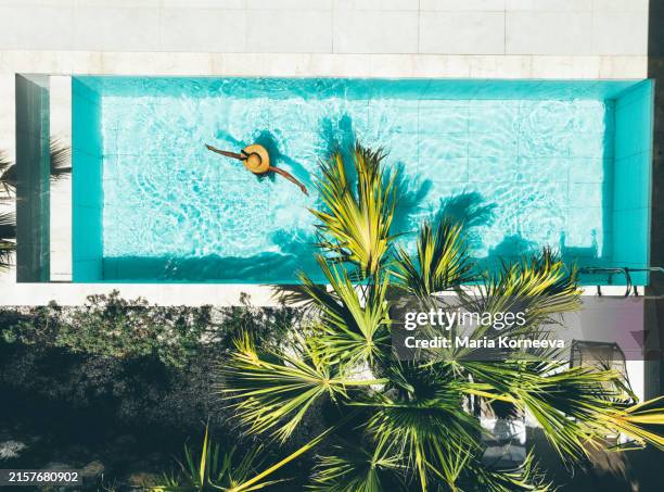 woman in straw hat relaxing in the pool. - sun tan pool stock pictures, royalty-free photos & images