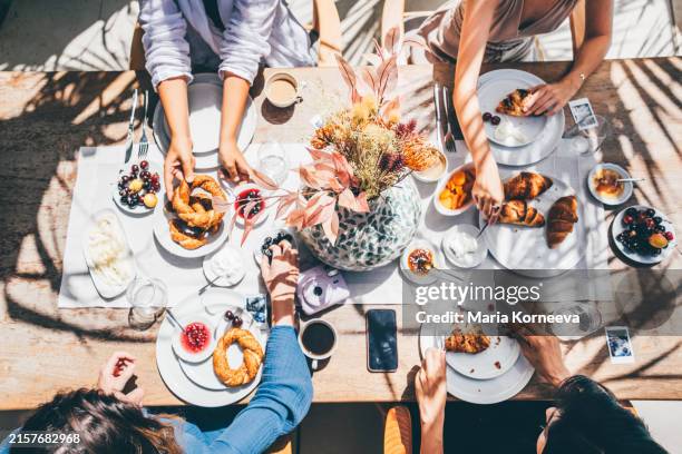 group of girlfriends having breakfast together on the patio. female friends sharing breakfast on the patio of luxury suite at tropical resort. - brunch fotografías e imágenes de stock