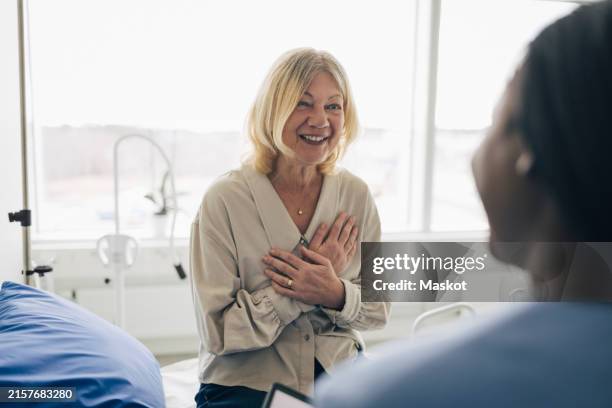 happy mature woman receiving good news from doctor during visit at hospital - boa notícia imagens e fotografias de stock