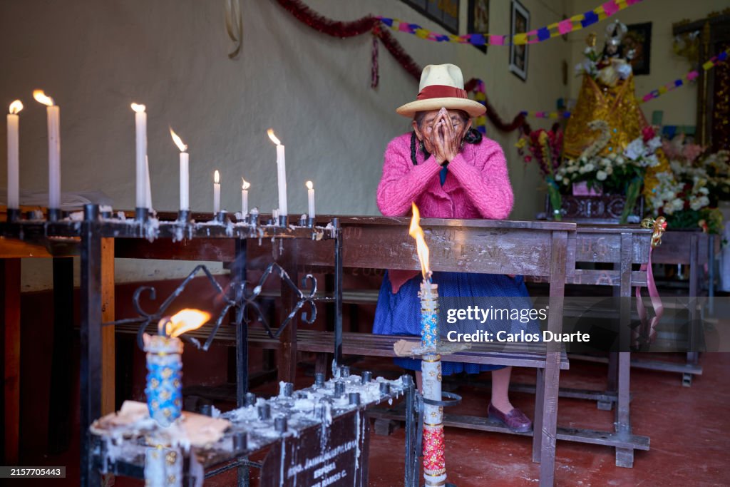 Peruvian elderly woman of the Quechua ethnic group praying with her hands on her face on her knees in the church