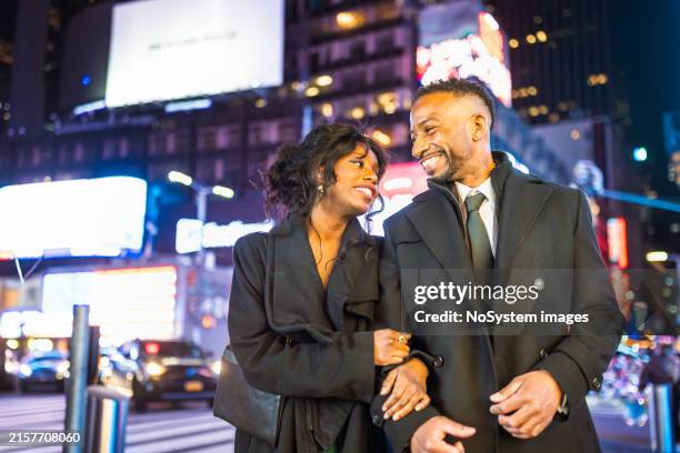 walking to the theatre in times square at night - couple crossing street stock pictures, royalty-free photos & images