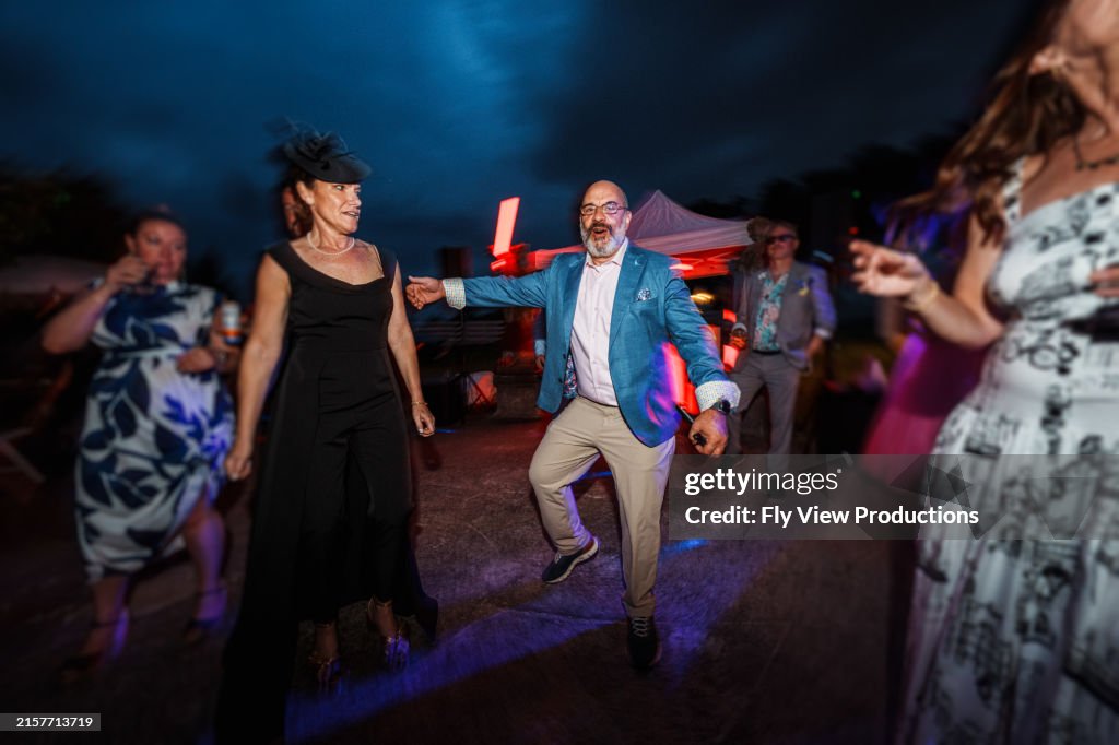 Cheerful group of adults having fun dancing at wedding reception