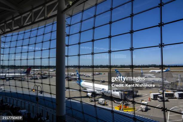 People sit in the central terminal looking out towards Alaska Airline planes at Seattle-Tacoma International Airport on June 19, 2024 in Seattle,...