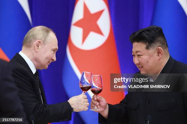 In this pool photograph distributed by the Russian state agency Sputnik, Russian President Vladimir Putin and North Korean leader Kim Jong Un toast...