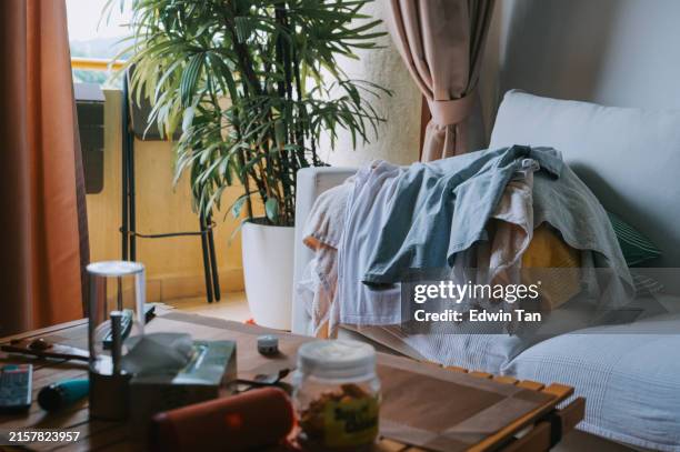 messy clothing stacked on sofa in apartment - tidy room stock pictures, royalty-free photos & images