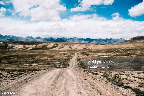 nubes sobre la carretera de montaña a lo largo de la tundra de las tierras altas de tien shan - montañas de tien shan fotografías e imágenes de stock