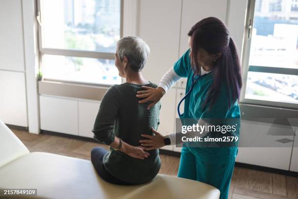 cuidado compasivo: fisioterapeuta ayuda a las personas mayores en la recuperación - columna vertebral fotografías e imágenes de stock