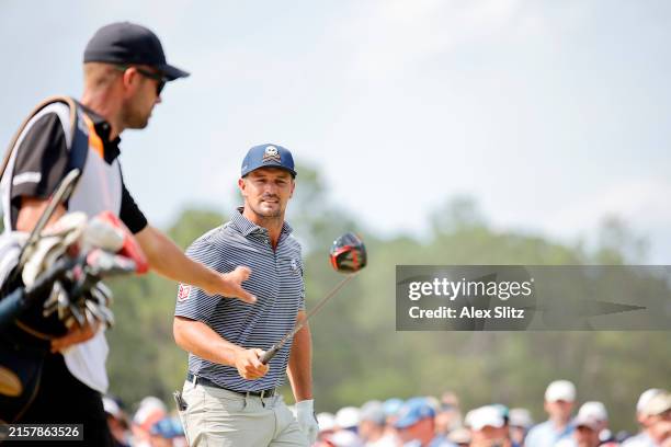 Bryson DeChambeau of the United States hands his driver to his caddie Gregory Bodine after hitting a tee shot on the eighth hole during the final...