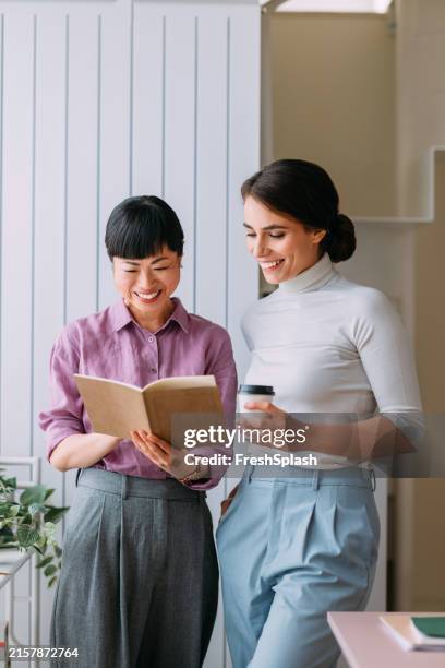 happy coworkers reading book and enjoying coffee break - workplace wellbeing stock pictures, royalty-free photos & images