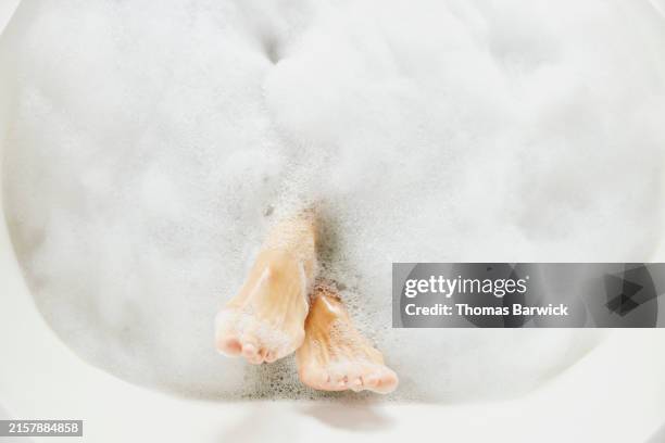medium shot overhead view woman's feet relaxing in bubble bath - relaxing bubble bath stock pictures, royalty-free photos & images