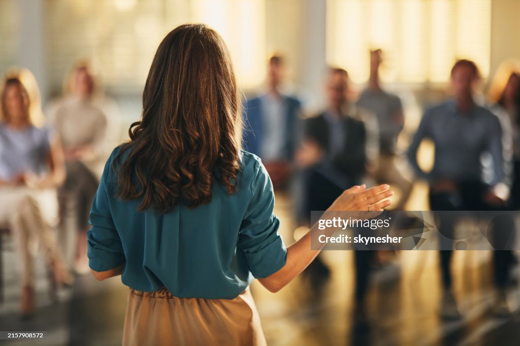 Back view of a businesswoman leading a seminar in board room.