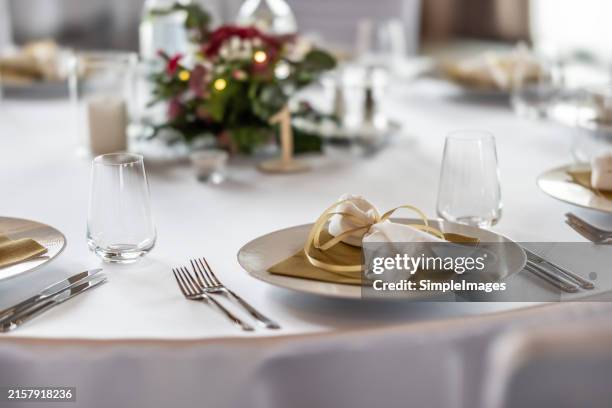 a wedding table covered with a white tablecloth, decorated with flowers, candles, glasses and cutlery. - cerimonia foto e immagini stock