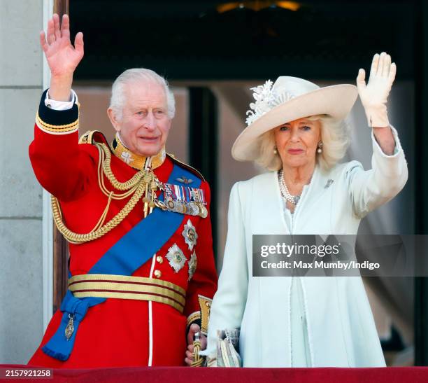 King Charles III, wearing his Irish Guards uniform, and Queen Camilla watch an RAF flypast from the balcony of Buckingham Palace after attending...