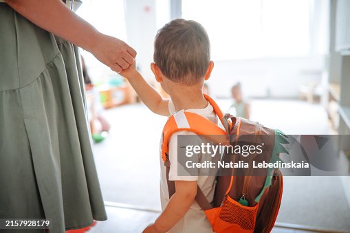 Asian toddler arriving at kindergarten with mom, starting adjustment to new children's group Asian toddler arriving at kindergarten with mom, starting adjustment to new children's group