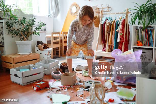 child in messy living room, cleaning up trash and toys on the floor - folgen bewegungsaktivität stock-fotos und bilder