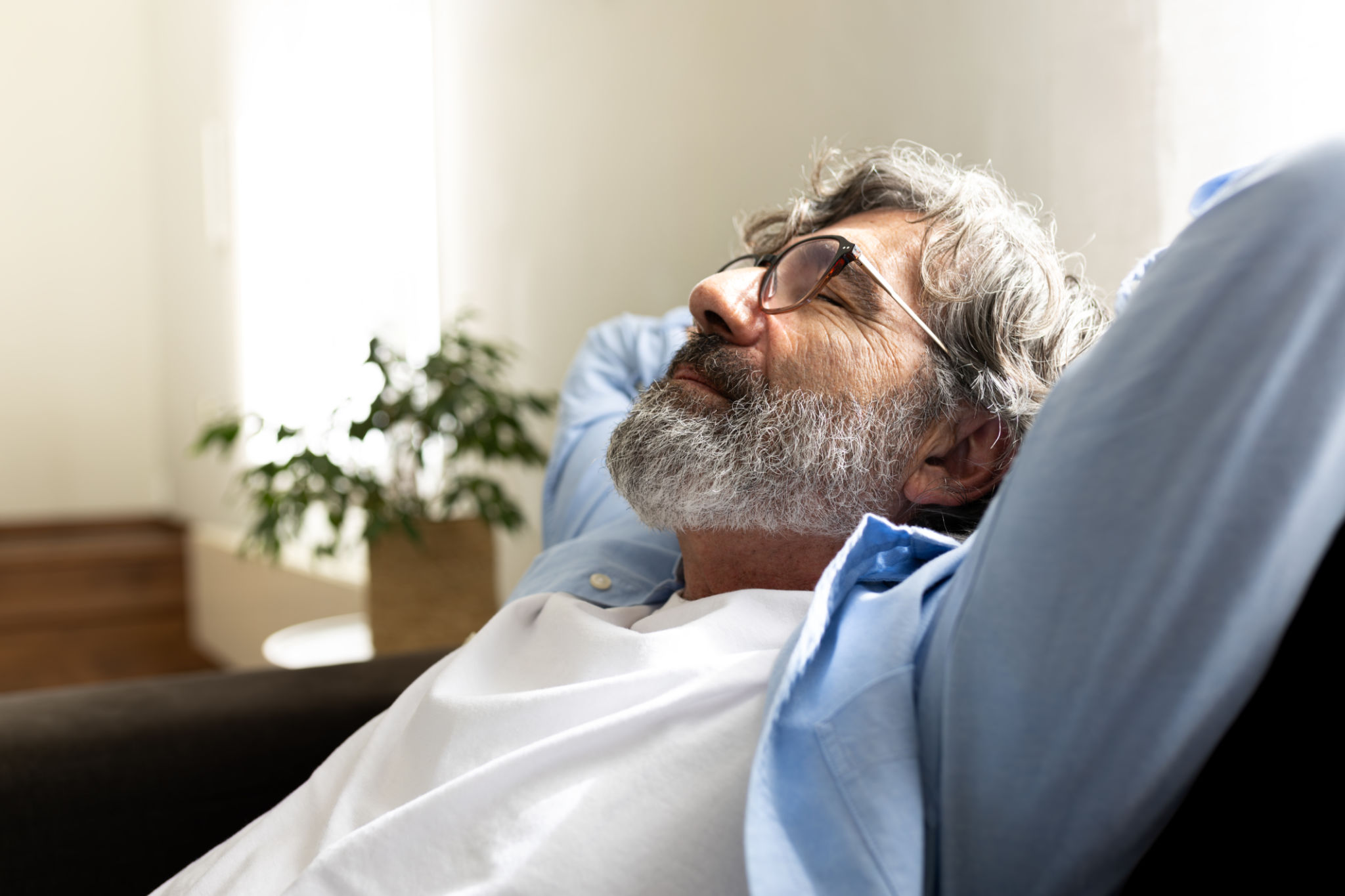 Mature man relaxing at home sitting on the sofa with hands behind the head feeling satisfaction. Copy space Mature man relaxing at home sitting on the sofa with hands behind the head feeling satisfaction. Copy space