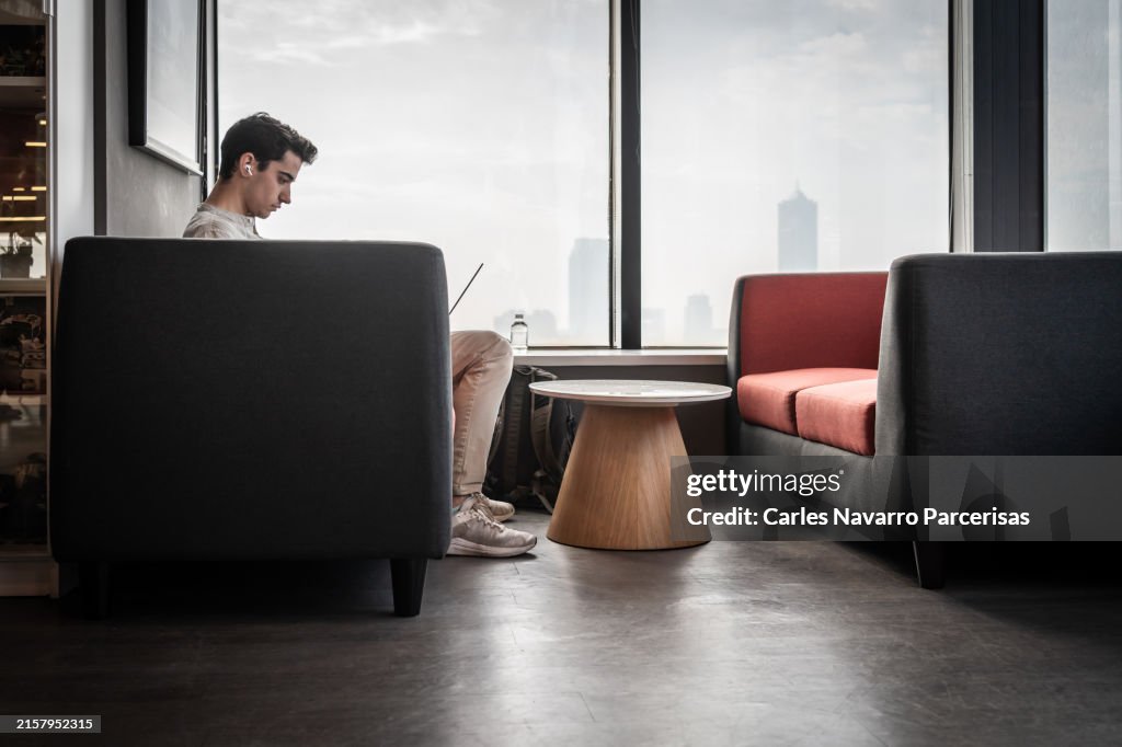 Man working on his laptop in a modern office overlooking the city.