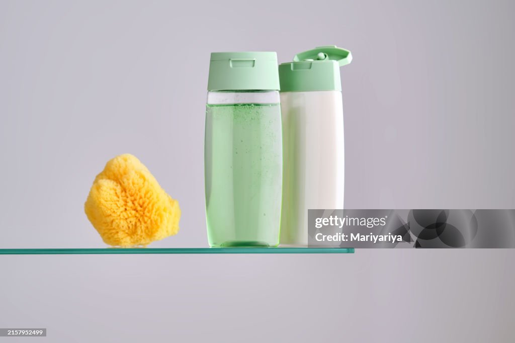 Shampoo and hair conditioner on a glass shelf in the bathroom.