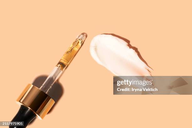 glass pipette with face serum, beauty product ampoule or essential oil with oxygen aqua bubbles and a smear face cream, refreshing hydration water cream, face gel, hair mask, hand cream on a pastel beige orange peach color color. - retinol stock pictures, royalty-free photos & images