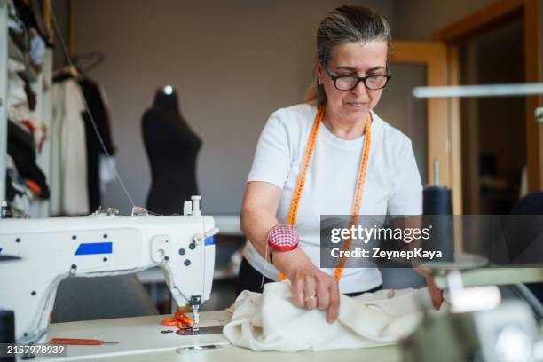 die schneiderin näht den stoff an der nähmaschine - nähen stock-fotos und bilder