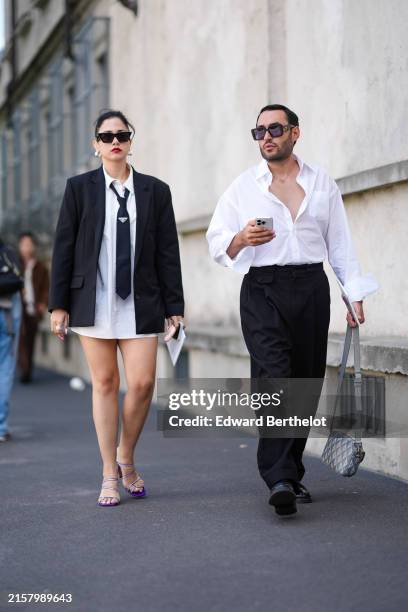 Guest wears sunglasses, earrings, a black oversize blazer jacket, a white shirt, a tie, outside Prada, during the Milan Fashion Week Menswear...