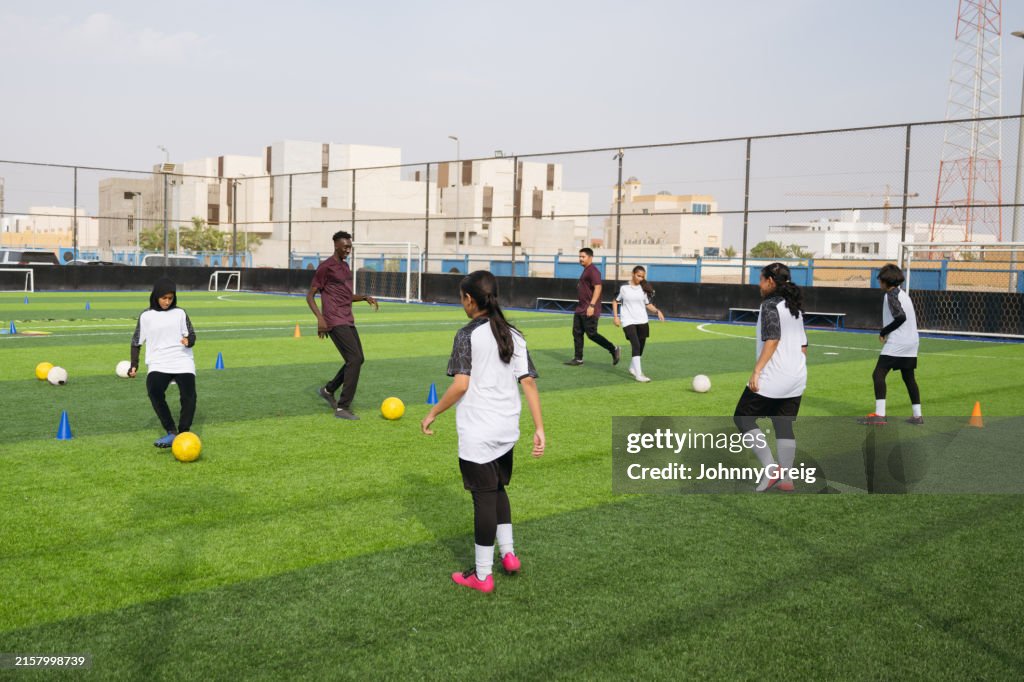 Coaches and female footballers exercising on sports field