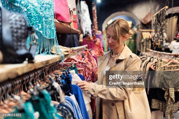 young woman browsing clothes in a small store. - boutique stock pictures, royalty-free photos & images