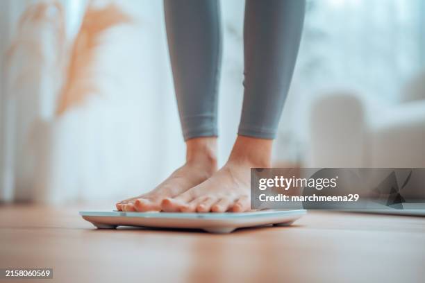 Closeup of feet, Young Asian woman standing on scales to measure her weight at home, Checking result of her slimming diet. Healthy living concept