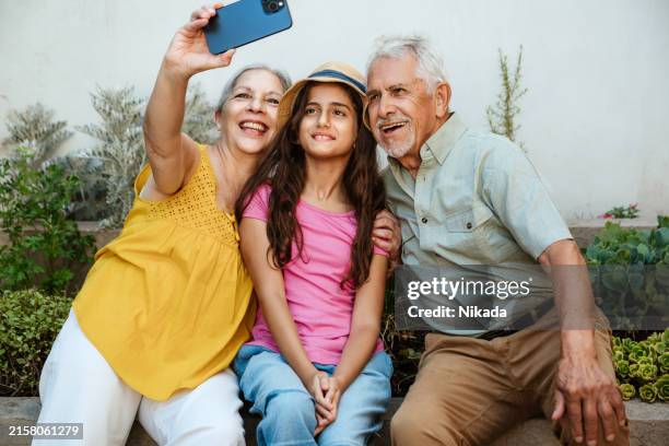 grandparents taking selfie with granddaughter in garden - family time outdoors stock pictures, royalty-free photos & images