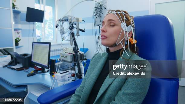 female patient undergoes sitting still eeg test in medical settings - neuropathy stock pictures, royalty-free photos & images