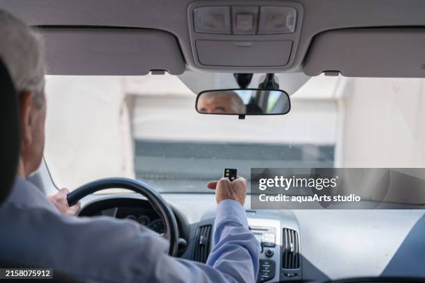 uomo in auto premendo il telecomando per aprire la porta automatica del garage - telecomando foto e immagini stock