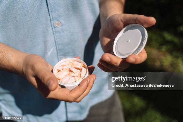 a man opens a plastic can of snus - nicotine stock pictures, royalty-free photos & images