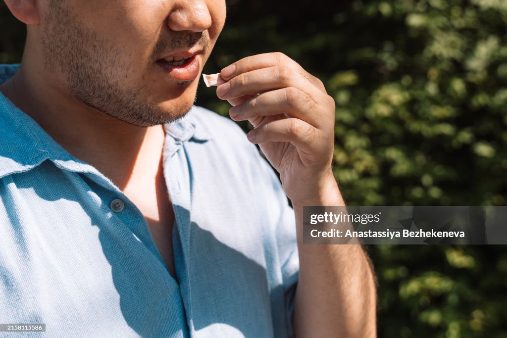 Man outdoors putting nicotine pouch into mouth