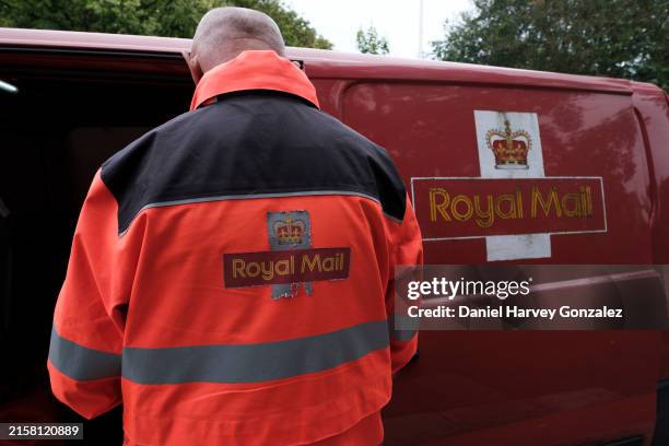 An employee of formerly state-owned postal service Royal Mail sorts parcels and letters in the back of his delivery van baring the postage company's...