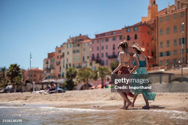 mother and daughter walking on the beach of menton, alpes-maritimes, france - menton stock pictures, royalty-free photos & images