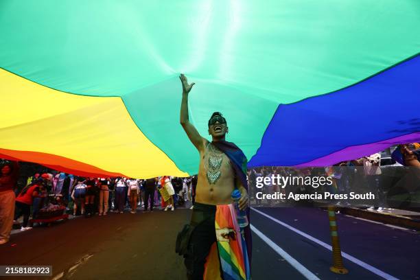 Persons shouts slogans below an LGTBI+ flag during the 2024 Quito Pride Parade on June 22, 2024 in Quito, Ecuador.