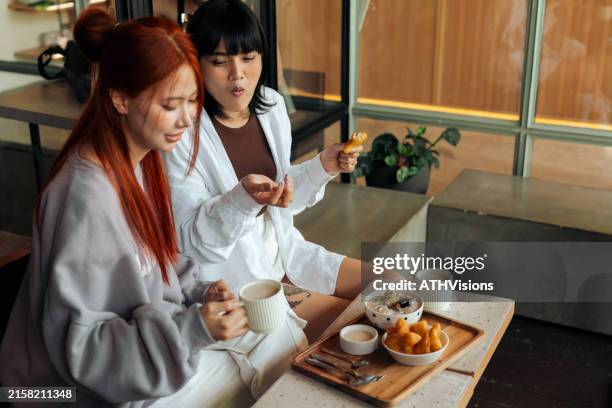 two friends sit at a café table, enjoying snacks and coffee together. they are engaged in conversation and enjoying their time. - soya milk stock pictures, royalty-free photos & images