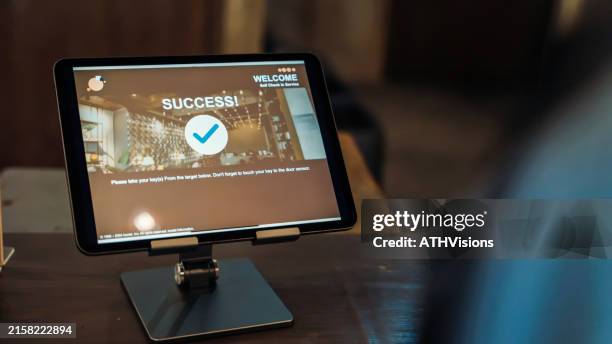 un écran de tablette affiche un enregistrement automatique réussi dans une auberge de jeunesse, soulignant la commodité des services d’enregistrement numérique. - matériel-denregistrement photos et images de collection