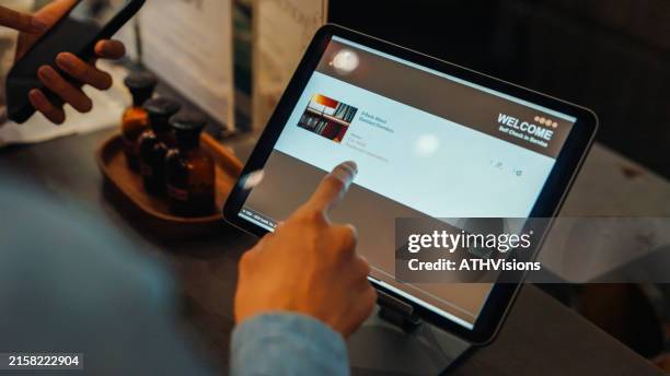 un client utilise une borne d’enregistrement en libre-service dans une auberge de jeunesse, sélectionnant les options de chambre sur une tablette. le processus est simplifié et efficace. - matériel-denregistrement photos et images de collection