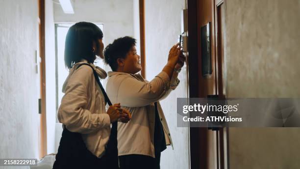lgbt couple using smart phone open and unlock a hostel door - digitale authenticatie stockfoto's en -beelden