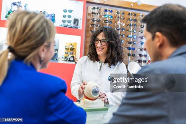 optometrista explicando un modelo de ojo a los pacientes. - condición fotografías e imágenes de stock