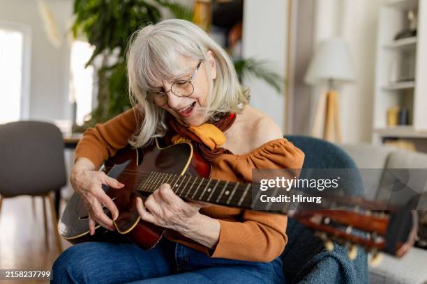 charming senior woman playing acoustic guitar - musikinstrument bildbanksfoton och bilder