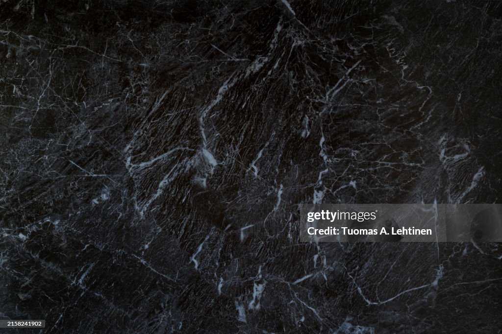 Close-up of dark gray, almost black, smooth and natural textured marble pattern background.
