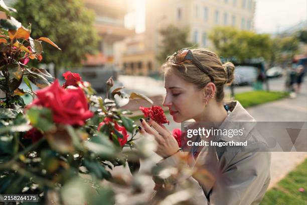 teenage girl enjoying beautiful rose flowers in the jardins biovès in town of menton. - odorat photos et images de collection