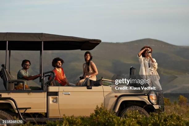 young man looking through binoculars near friends - digital camera stock pictures, royalty-free photos & images