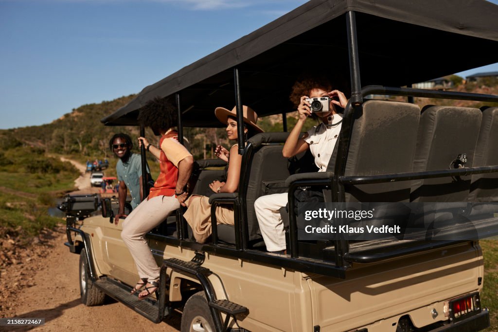 Woman photographing while sitting with friends in vehicle